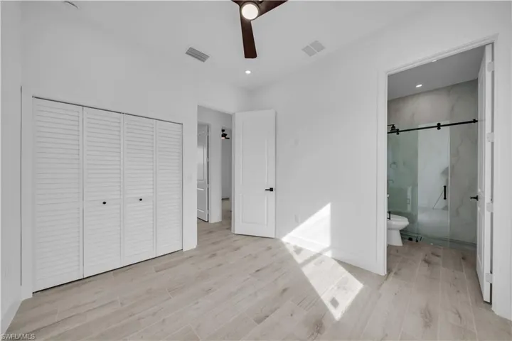 Unfurnished bedroom featuring wood tiled floors, a closet, ceiling fan, ensuite bath, and recessed lighting