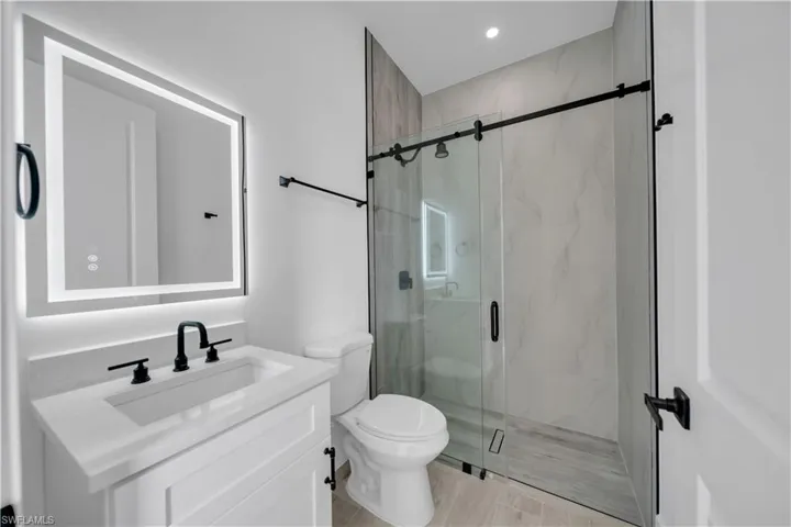 Bathroom featuring vanity, a marble finish shower, and recessed lighting