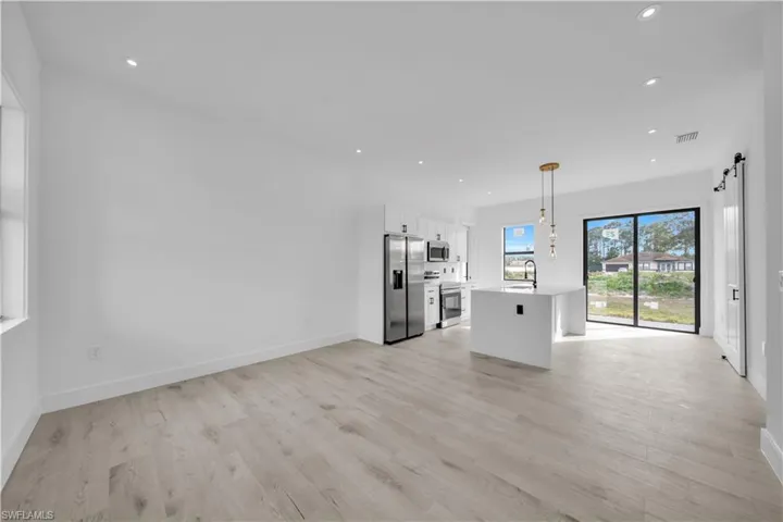 Unfurnished living room with a barn door, recessed lighting, and light wood-style flooring