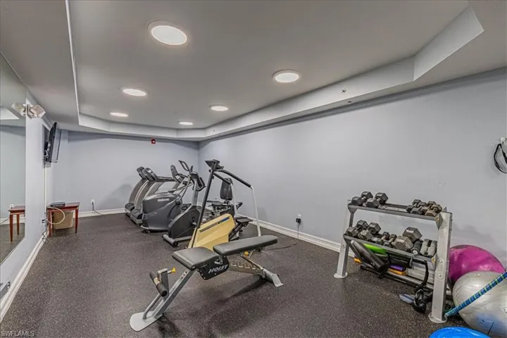 Exercise room featuring recessed lighting and a raised ceiling