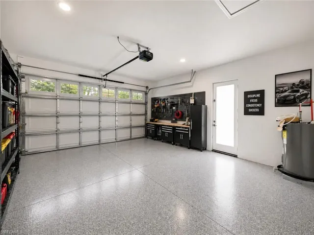 Virtually staged : Garage space featuring an epoxy-coated floor, overhead lighting, and an automatic garage door with upper window panels