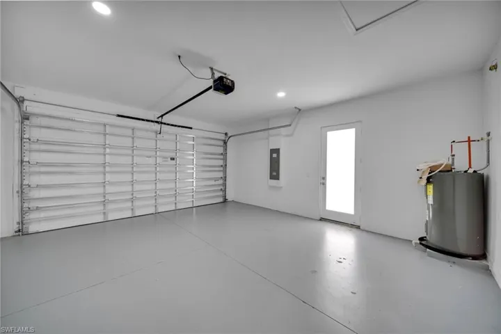Spacious garage featuring a light gray painted concrete floor, white walls, and an automatic garage door opener