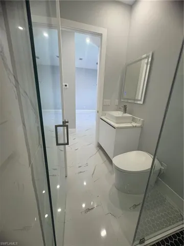 Bathroom with vanity, marble finish floor, toilet, and a shower stall