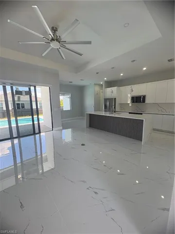 Unfurnished living room with a tray ceiling, visible vents, baseboards, and marble finish floor