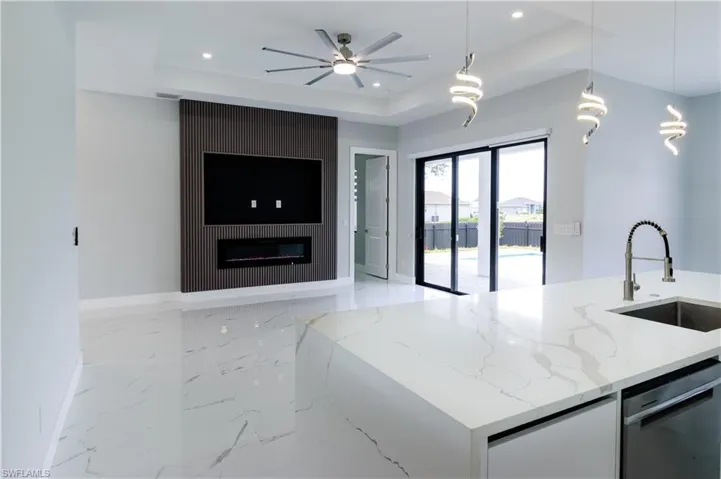 Kitchen featuring dishwasher, a sink, baseboards, a tray ceiling, and recessed lighting