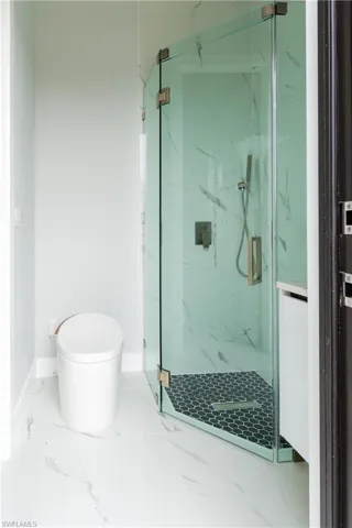 Full bath with baseboards, marble finish floor, a marble finish shower, and toilet