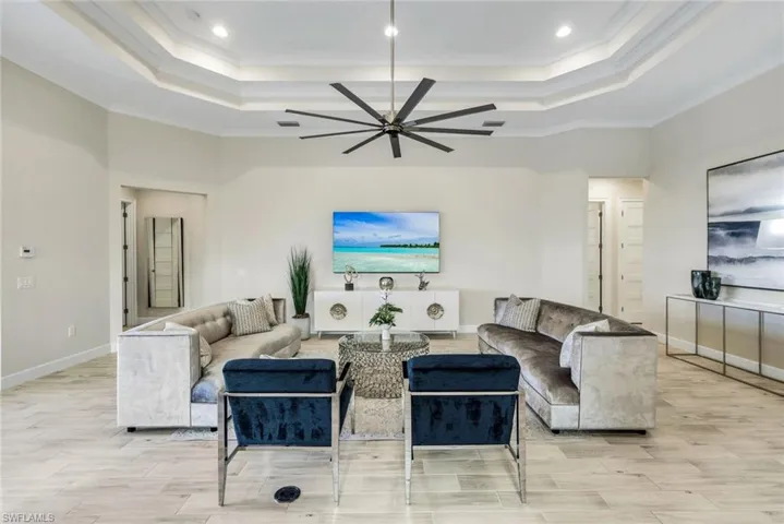 Living area featuring ceiling fan, wood tiled floors, and ornamental molding