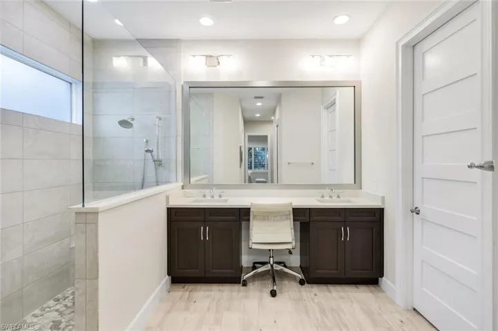 Full bathroom featuring double vanity, a walk in shower, light wood-style flooring, and recessed lighting