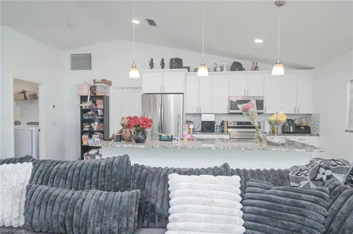 Kitchen featuring pendant lighting, stainless steel appliances, and white cabinets