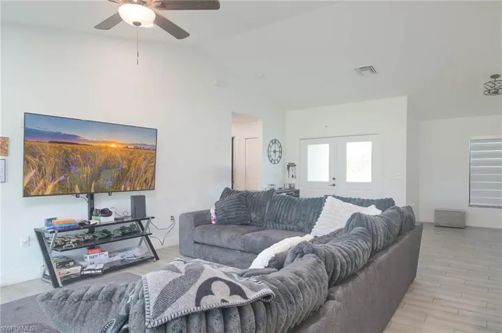 Living room featuring lofted ceiling, ceiling fan, french doors, and light hardwood / wood-style flooring
