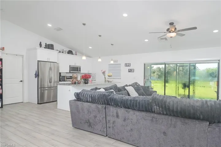 Living room featuring ceiling fan, light hardwood / wood-style floors, and high vaulted ceiling