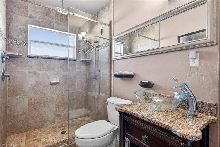 Full bathroom featuring vanity, a stall shower, a textured wall, and plenty of natural light