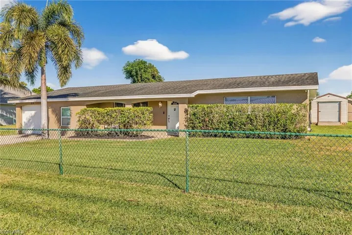 Ranch-style home featuring stucco siding, a fenced front yard, a storage shed, and a garage