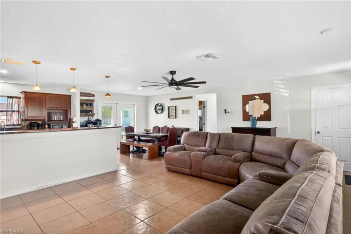 Living room with a textured ceiling, a ceiling fan, french doors, and light tile patterned floors