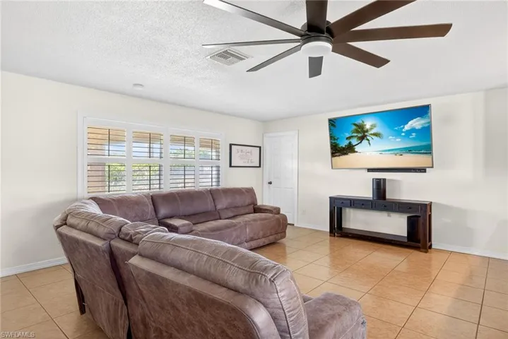 Living room featuring light tile patterned flooring, a textured ceiling, and a ceiling fan