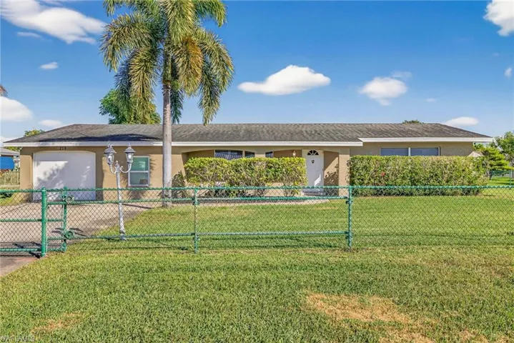 Ranch-style house with stucco siding, an attached garage, a fenced front yard, and a gate