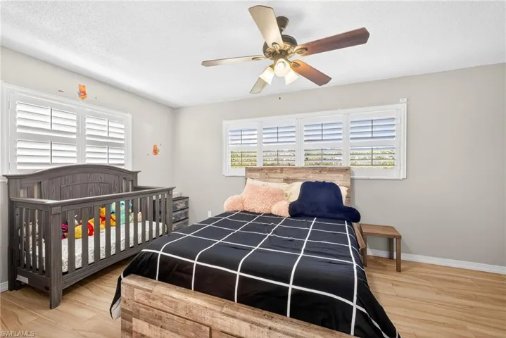 Bedroom featuring a textured ceiling, multiple windows, ceiling fan, and light wood finished floors