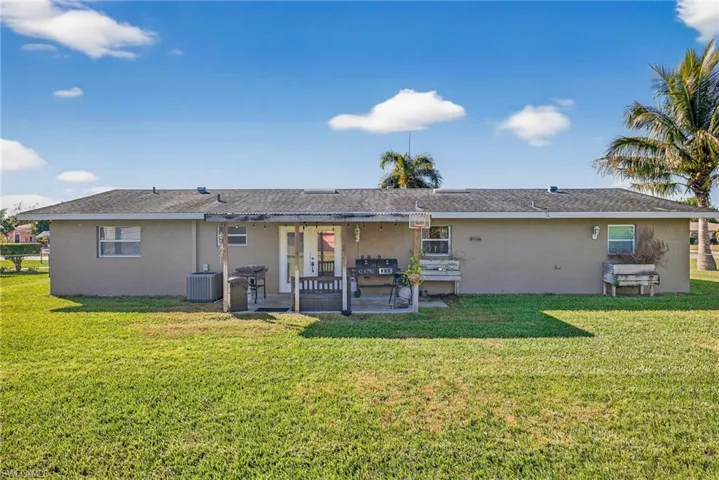Back of house with stucco siding, a yard, and a patio