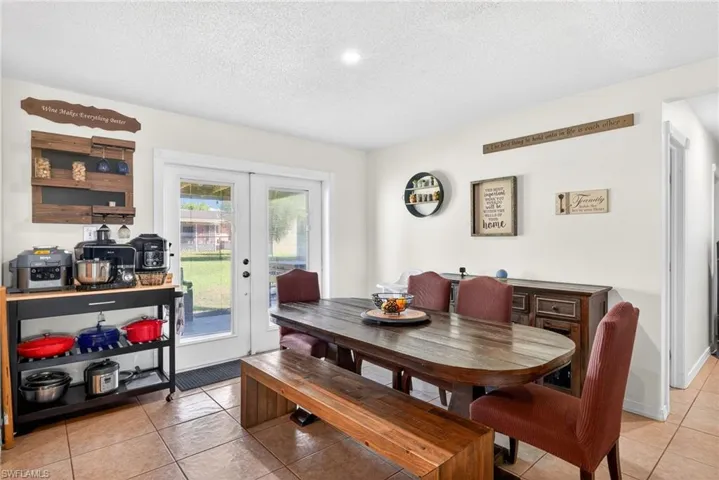 Dining space with light tile patterned flooring, a textured ceiling, and french doors