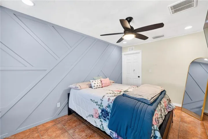 Tiled bedroom with recessed lighting, a ceiling fan, and a decorative wall