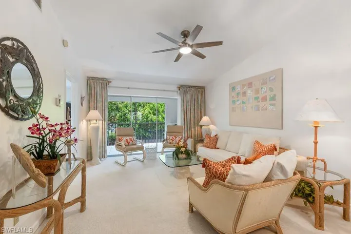 Living space featuring a neutral color palette, new ceiling fan with integrated lighting, and a glass sliding door opening to a private screened lanai area.
