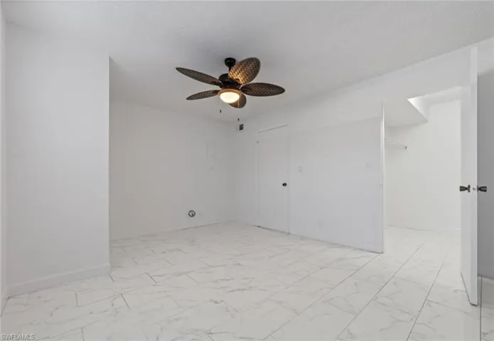 Unfurnished room featuring light marble finish floors, a ceiling fan, and a textured ceiling