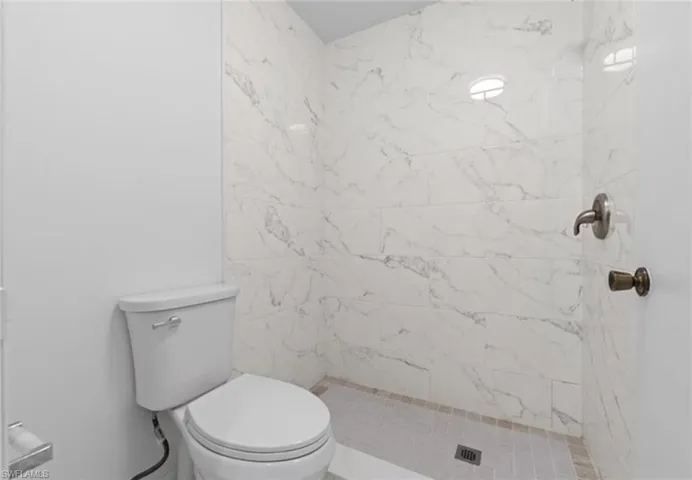 Bathroom with a marble finish shower and toilet