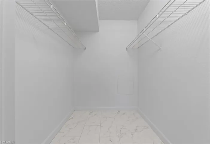 Walk in closet with light marble finish flooring