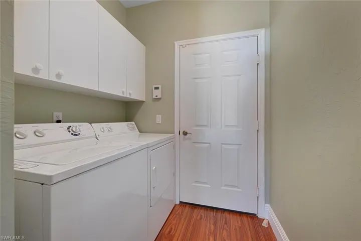 Washroom with washing machine and dryer, light wood-style flooring, and cabinet space