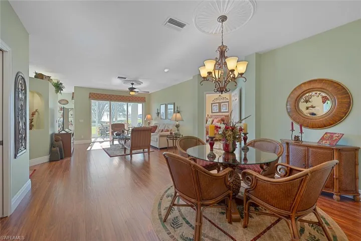 Dining area with ceiling fan, wood finished floors, and a chandelier