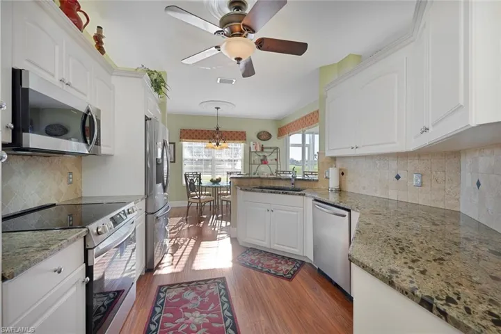 Kitchen with tasteful backsplash, appliances with stainless steel finishes, a peninsula, and dark stone countertops