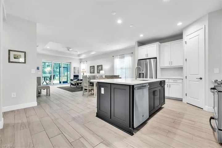 Kitchen island featuring a light-toned countertop, dark cabinetry, and integrated stainless steel dishwasher