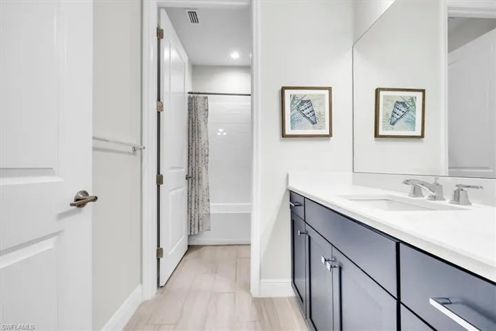 Bathroom featuring a dark wood-finish vanity with a white countertop and undermount sink, brushed nickel fixtures, and a large wall mirror