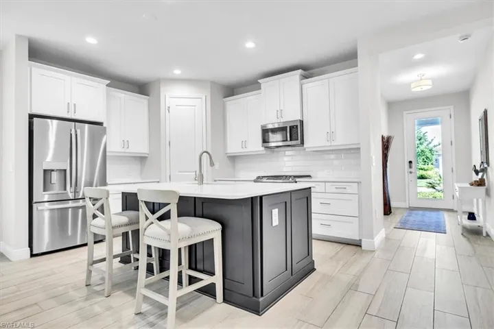 Modern kitchen featuring a central island with a contrasting dark base, white countertops, and a stainless steel appliance suite