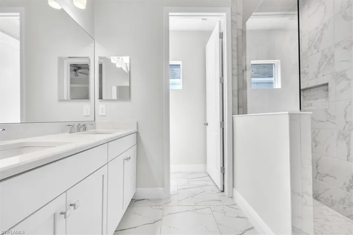 Bathroom featuring a double vanity with white cabinetry, light-toned countertops, and brushed nickel fixtures