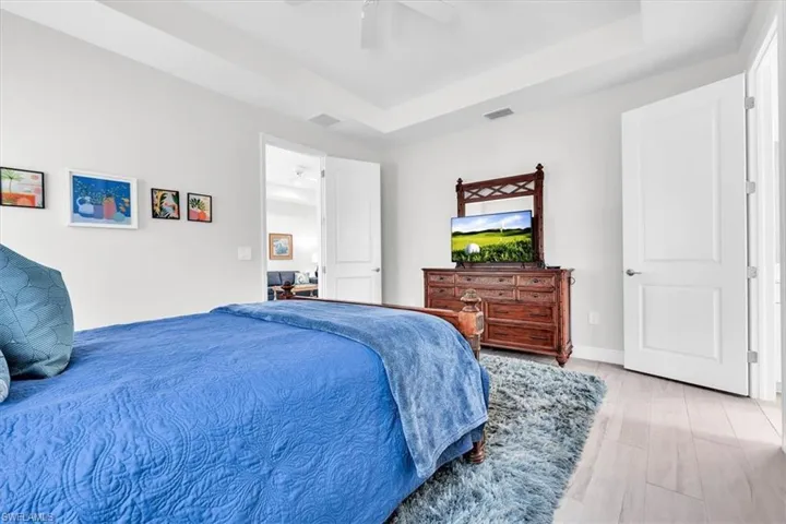 Recessed lighting illuminates a tray ceiling and light-toned walls