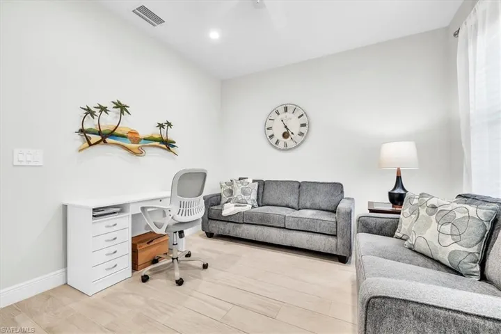 Bright room featuring light wood-finish flooring, white walls, and a ceiling fan