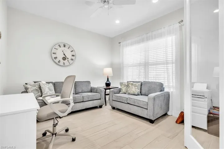 Versatile interior space featuring light wood-finish flooring, a contemporary ceiling fan, recessed lighting, and a large window with blinds and sheer curtains
