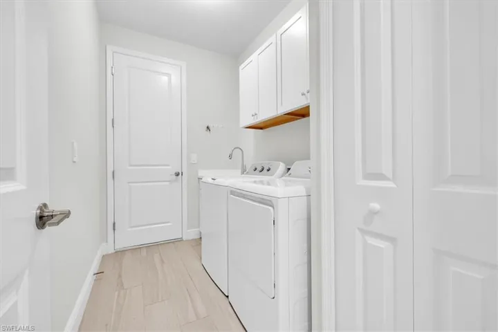 Dedicated laundry room featuring white cabinetry, a built-in countertop, and wood-finish flooring