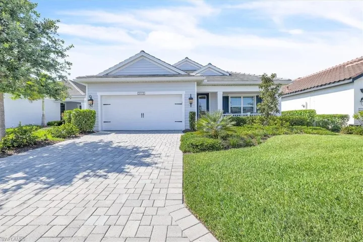 Light blue siding exterior featuring a covered entry, an attached garage, and a paver driveway