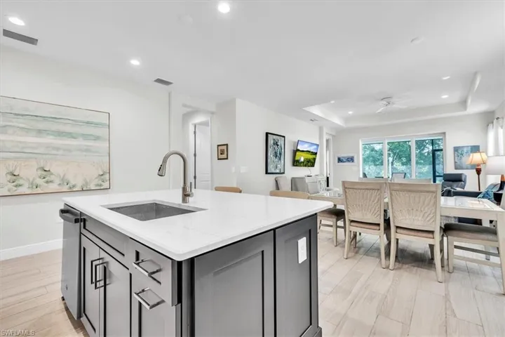 Kitchen island featuring a white countertop with an undermount sink and a brushed nickel faucet