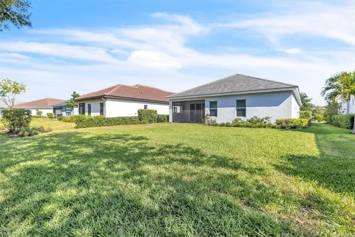 Expansive green lawn with established landscaping, screened patio, and a tiled roofline