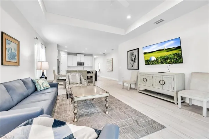 Open-concept living space featuring wood-finish flooring, recessed lighting, and a tray ceiling