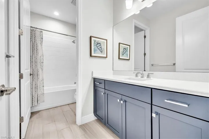 Bathroom vanity featuring blue cabinetry, a white countertop, and an integrated sink with a chrome faucet