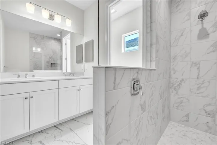 Walk-in shower with full-height marble-look tile surround and chrome fixtures