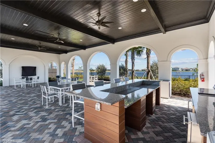 View of patio with a ceiling fan, an outdoor bar and dining area, a water view, and exterior kitchen