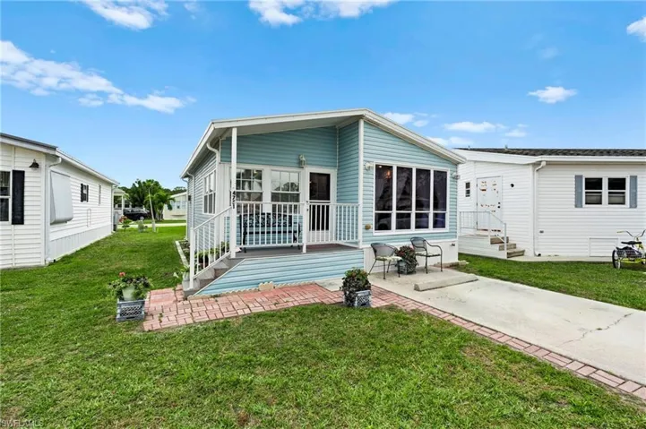 Rear view of property featuring a lawn, a patio area, and a wooden deck