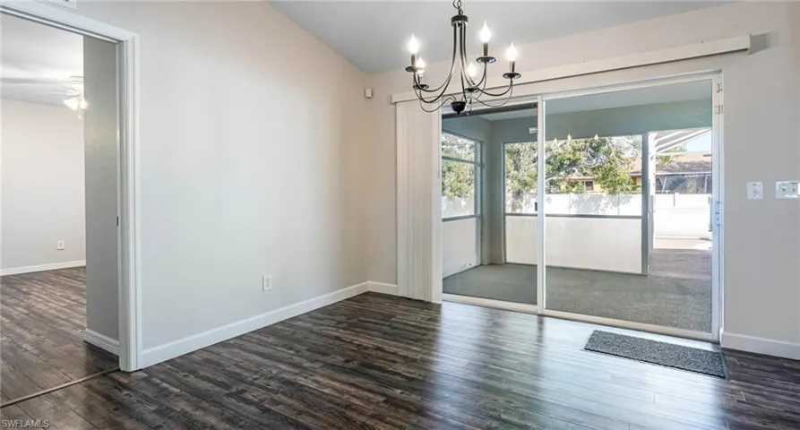 Dining room with dark LPV floors, ceiling fan with chandelier, and vaulted ceiling