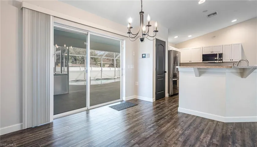 Kitchen featuring cathedral ceiling, appliances with stainless steel finishes, LPV flooring, a breakfast bar, and new chandelier