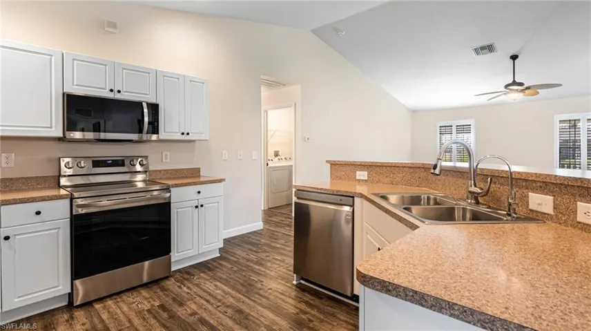 Kitchen with white cabinetry, cathedral ceilings, new appliances with stainless steel finishes, sink, and ceiling fan